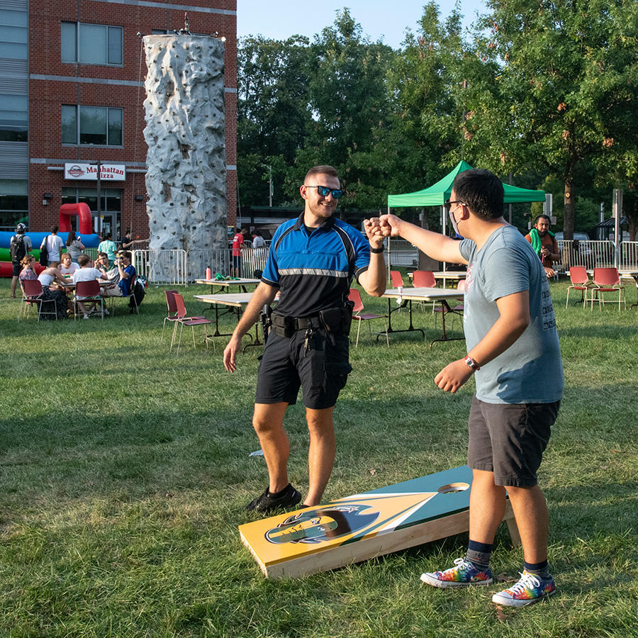 A saftety officer fistbumps a student at an outdoor event.