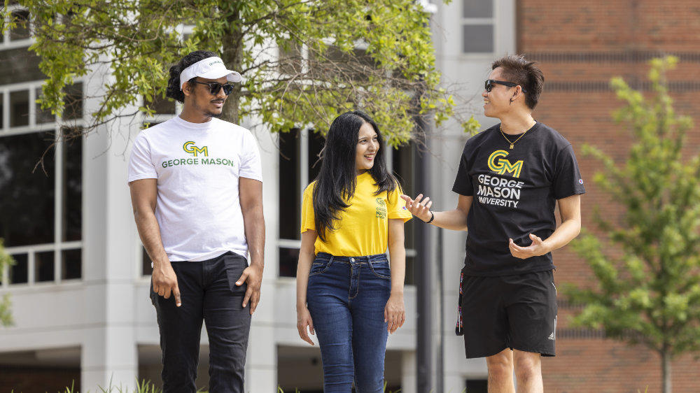 Students walk outside the JC on the Fairfax campus wearing shirts bearing the George Mason University Logo